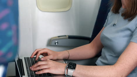 mujer irreconocible trabajando en una computadora portátil en un avión
