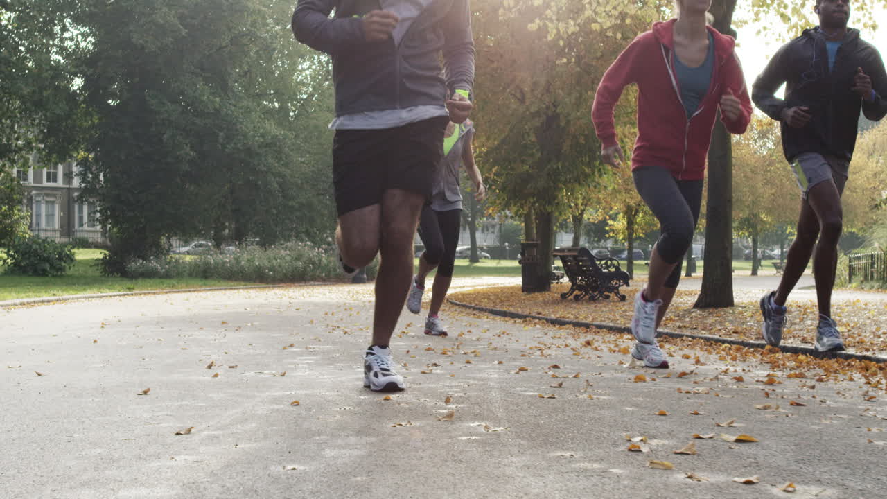 Group of runners running in park wearing wearable technology connected devices
