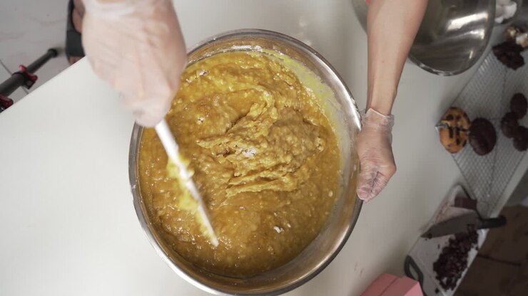 Baker Mixing Batter With Floury Lumps In Stainless Steel Mixing Bowl