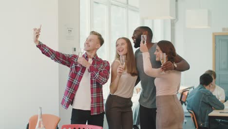 gente sonriente haciendo selfies en el espacio de trabajo. equipo alegre posando para la cámara.