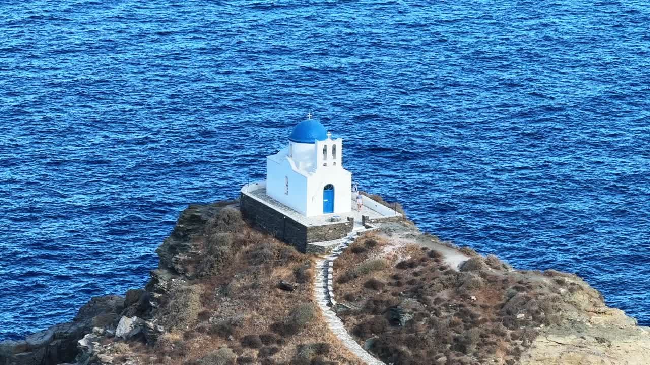 A church perched on a rocky outcrop, surrounded by summer waves and the open sea.
