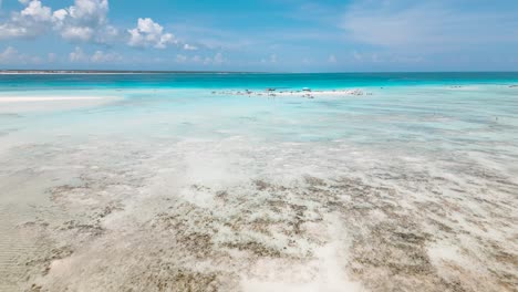 4K-flying-drone-footage-above-white-sandbanks-coast-with-beautiful-transparent-rippled-waves-washing-coral-reefs-atoll-near-Mnemba-Island,-Tanzania