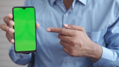 close up de la mano de un joven usando un teléfono inteligente con pantalla verde