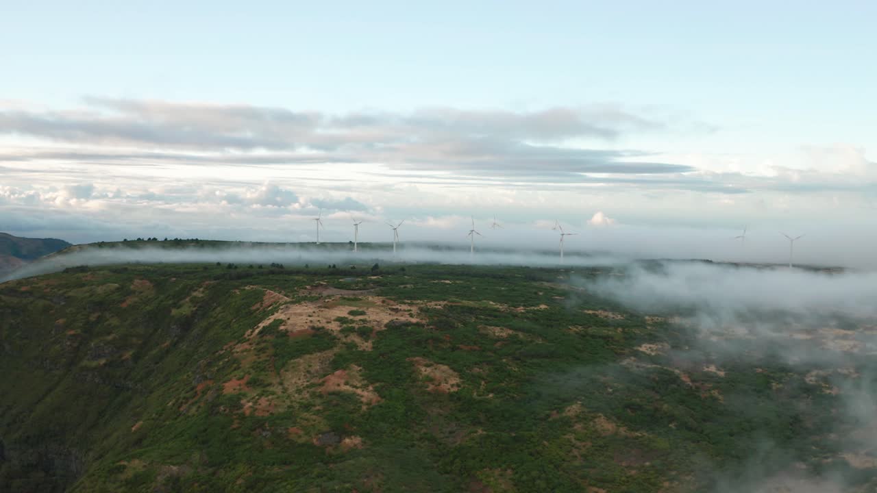 aéreo en medio de la montañosa madeira con nubes bajas y molinos de viento distantes
