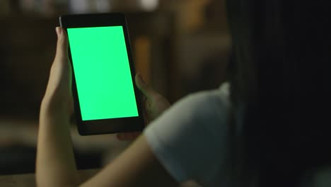 una adolescente está usando una tableta con pantalla verde en modo paisaje por la noche. estilo de vida casual.
