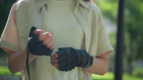 close-up of individual outdoors removing biker glove on right hand with gentle movement, background features blurred lush greenery