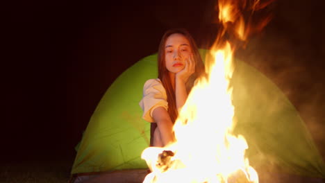 산불 앞에서 밤에 캠핑하는 아시아 젊은 여성의 근접 초상화