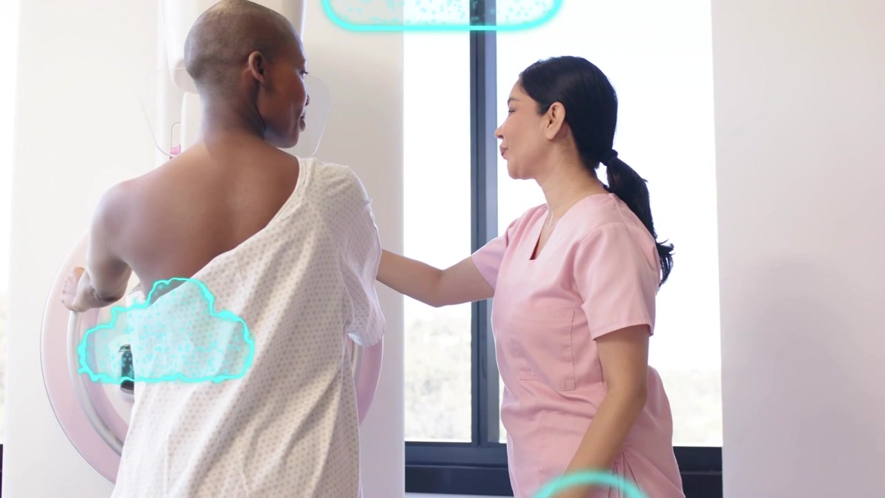 Assistant raising hands, guiding patient onto mammogram for breast scan while teal cloud drifting