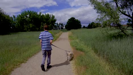 teen boy walking cute dog on a nature trail