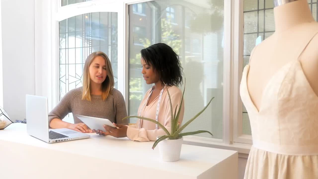 Kvindelige modedesignere diskuterer på en digital tablet