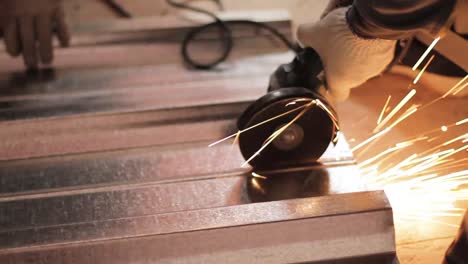 man cuts metal with a grinder and sparks fly