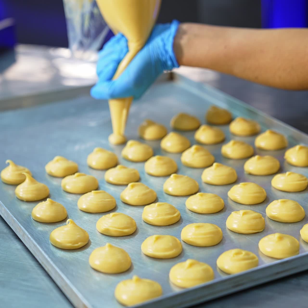 Confectioner in gloves squeezes liquid batter on the baking sheet. Sweets manufacturing at confectionary factory