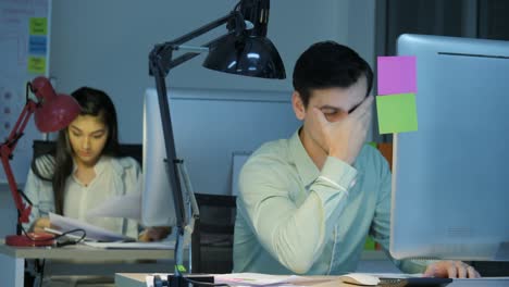 tired and stressed businessman and businesswoman are working late into the night at their office