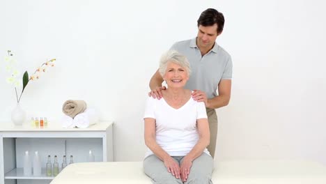 fisioterapeuta sonriendo a la cámara con el paciente mayor