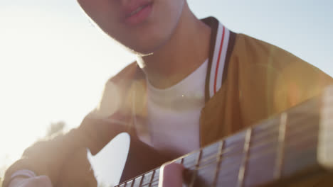 un joven tocando la guitarra en un techo con sus amigos