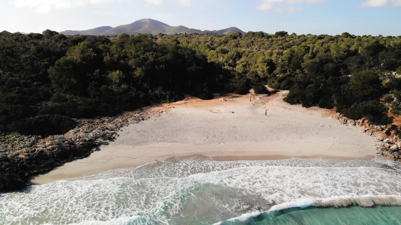 aerial drone shot of an empty hidden beach in Majorca and panning down to brilliant blue water in the Mediterranean