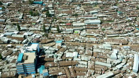 aerial tilt up shot of crowded urban slum area in kibera and modern skyline of nairobi in background during sunlight