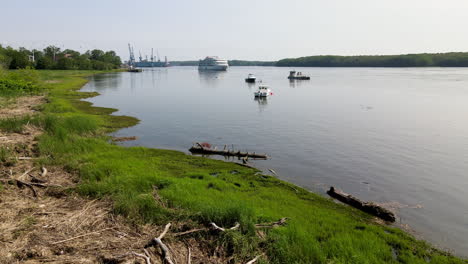 Tripod-shot-of-a-cruise-ship-on-the-Kennebec-River,-shows-grassy-shoreline-and-calm-river