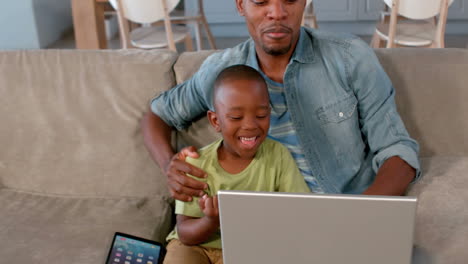 Padre-E-Hijo-Usando-Una-Computadora-Portátil-En-El-Sofá