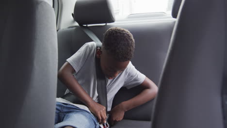 african american boy buckles up in the backseat of a car