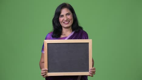 madura feliz hermosa mujer india sonriendo mientras muestra la pizarra