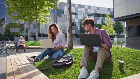 adult students study outside with laptop together. casual man talking friend