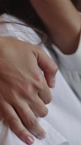 mujer acaricia y abraza a su novia con discapacidad en silla de ruedas. manos de una persona femenina en los hombros de su pareja en un primer plano de fondo borroso