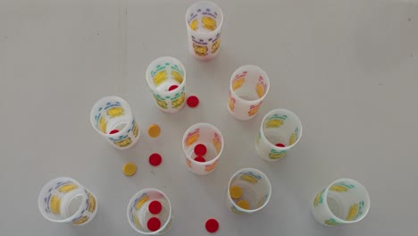 niños jugando con copas de plástico y monedas arrojadas a las copas