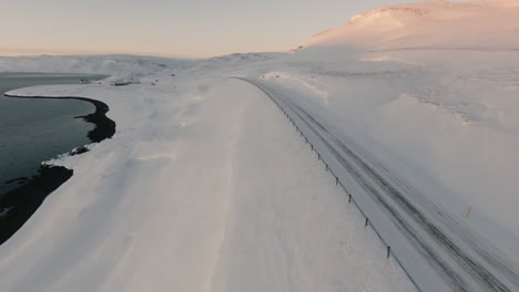 fpv dolly forward above frozen road leading towards house, winter mountain scape