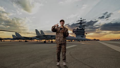 full body of asian man soldier smiling and pointing to smartphone in his hand while standing on aircraft carrier