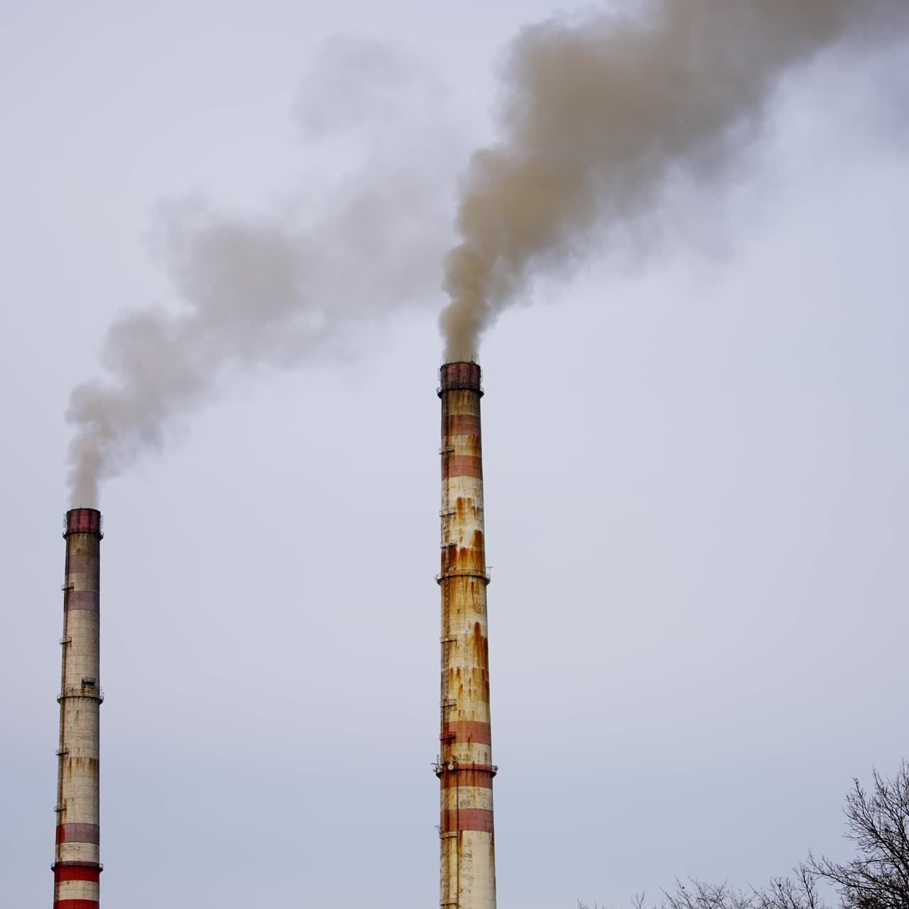 Industrial zone with large pipes. Thick white smoke is pouring in contrast to the sun. Pollution of the environment