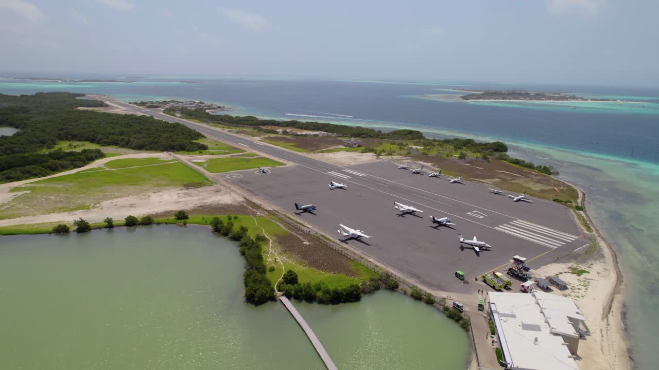 Drone pulls back revealing planes on runway, lagoon, sea, and nearby port in Los Roques, Venezuela.