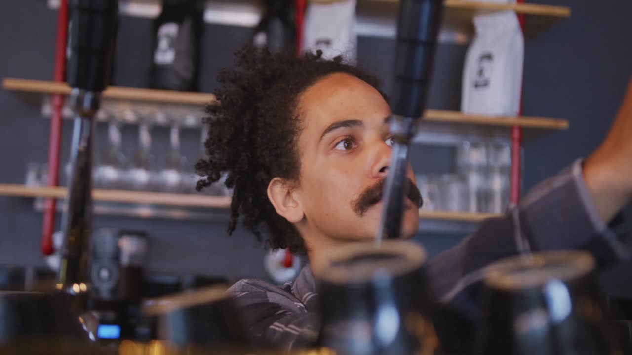 Barista uomo di etnia mista con i baffi che prepara caffè da asporto.