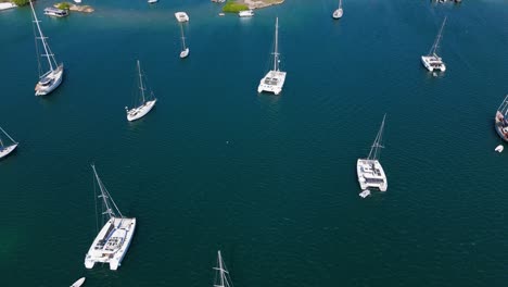 top-down aerial of multiple sailboats anchored in calm ocean waters, creating a peaceful and scenic view