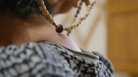 a prayer mala bead necklace is taken off by a client