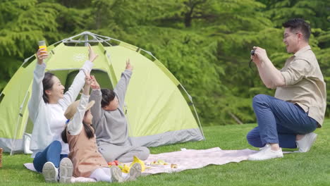 happy family in the outdoor outing having a picnic in the park, concept of destination, family travel and summer vacation or holidays