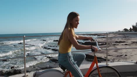 Seitenansicht-Eines-Kaukasischen-Mädchens,-Das-Am-Meer-Fahrrad-Fährt