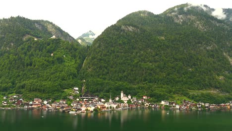 aerial view of hallstatt, austria, captured by drone, showcasing its picturesque lakeside homes, majestic mountains, and the unique charm of this enchanting alpine village.