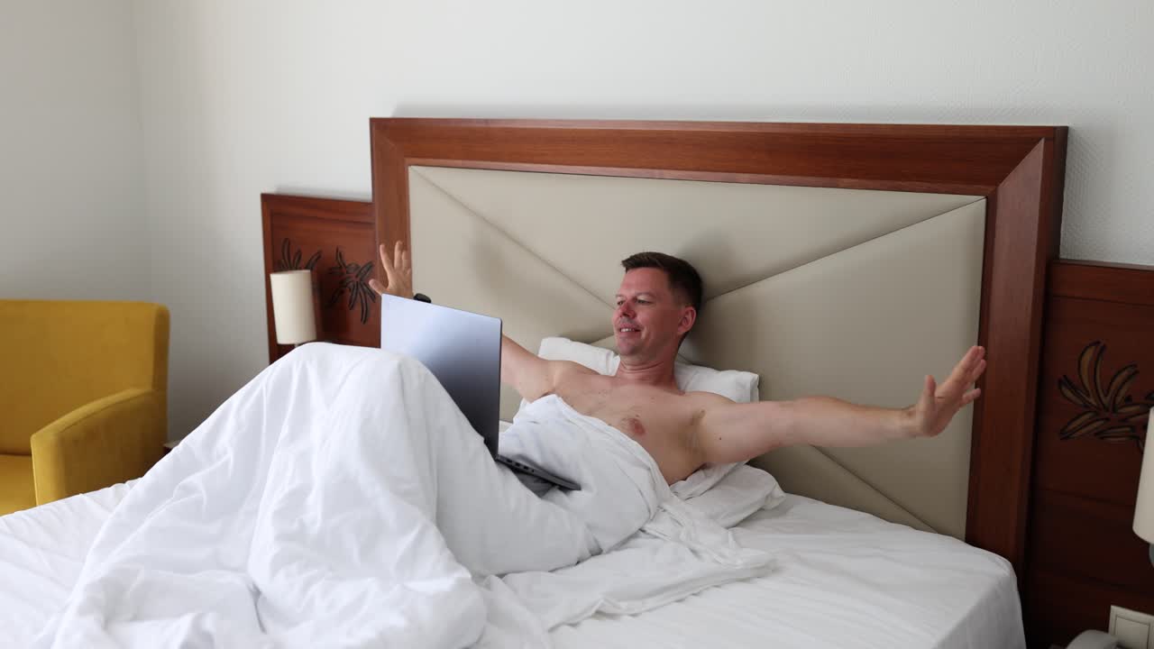 Man relaxing in bed with laptop