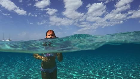 Adorable-young-little-girl-bathing-in-crystal-clear-sea-water,-France