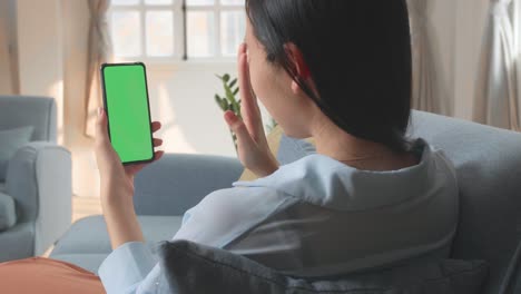 female video call while using smartphone with green screen display in living room, video in 4k