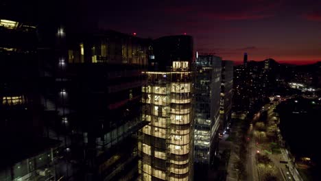 Luftaufnahme-Der-Errichtung-Moderner-Glasgebäude-Mit-Der-Skyline-Von-Santiago,-Chile-Im-Hintergrund,-Sonnenuntergang-Am-Costanera-Tower