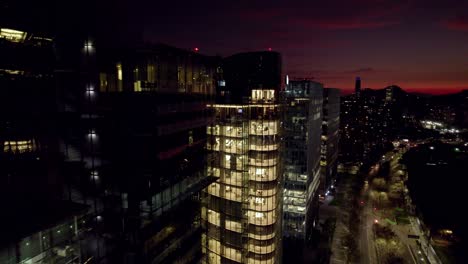 aerial view establishing of modern glass buildings with the skyline of santiago chile in the background, sunset costanera tower