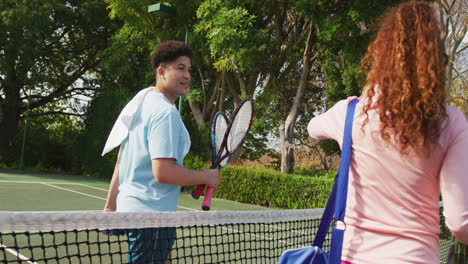 Video-of-happy-biracial-couple-playing-tennis-on-the-court