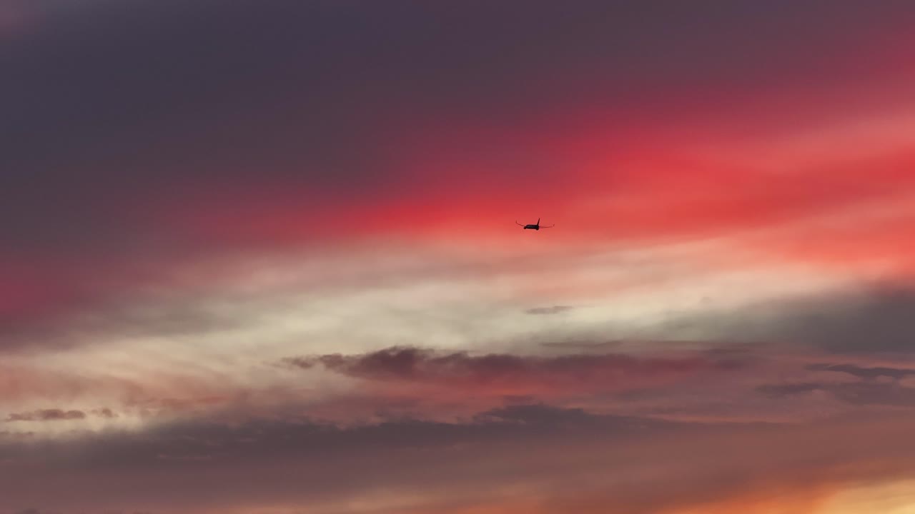 gran avión de carga volando a través de nubes púrpuras rosadas brillantes al atardecer telefoto aéreo estático