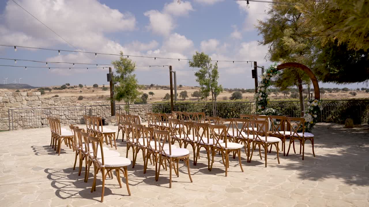 Un elegante allestimento per un matrimonio all'aperto presenta sedie di legno ben disposte di fronte a un paesaggio mozzafiato. L'ambiente sereno crea un'atmosfera perfetta per una cerimonia speciale.