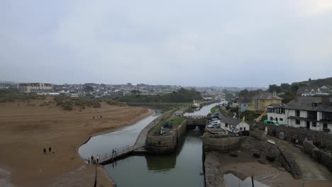 Bude-Cornwall-Canal-Y-Bloqueo-De-Imágenes-Aéreas-4k-Personas-Cruzan-Un-Pequeño-Puente-Drone-A-Lo-Largo-Del-Canal-Pasando-Barco-Amarrado