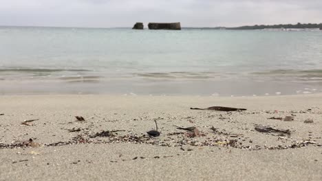 Sand-beach-in-San-Cataldo,-Italy-near-lecce-city-with-brick-wall-on-island-in-the-background-in-slow-motion