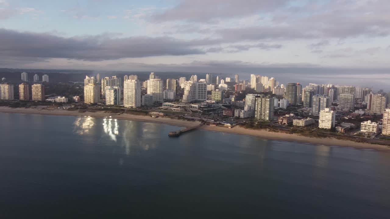 toma aérea del hermoso paisaje urbano de punta del este con edificios de gran altura, playa y océano atlántico durante la hora dorada