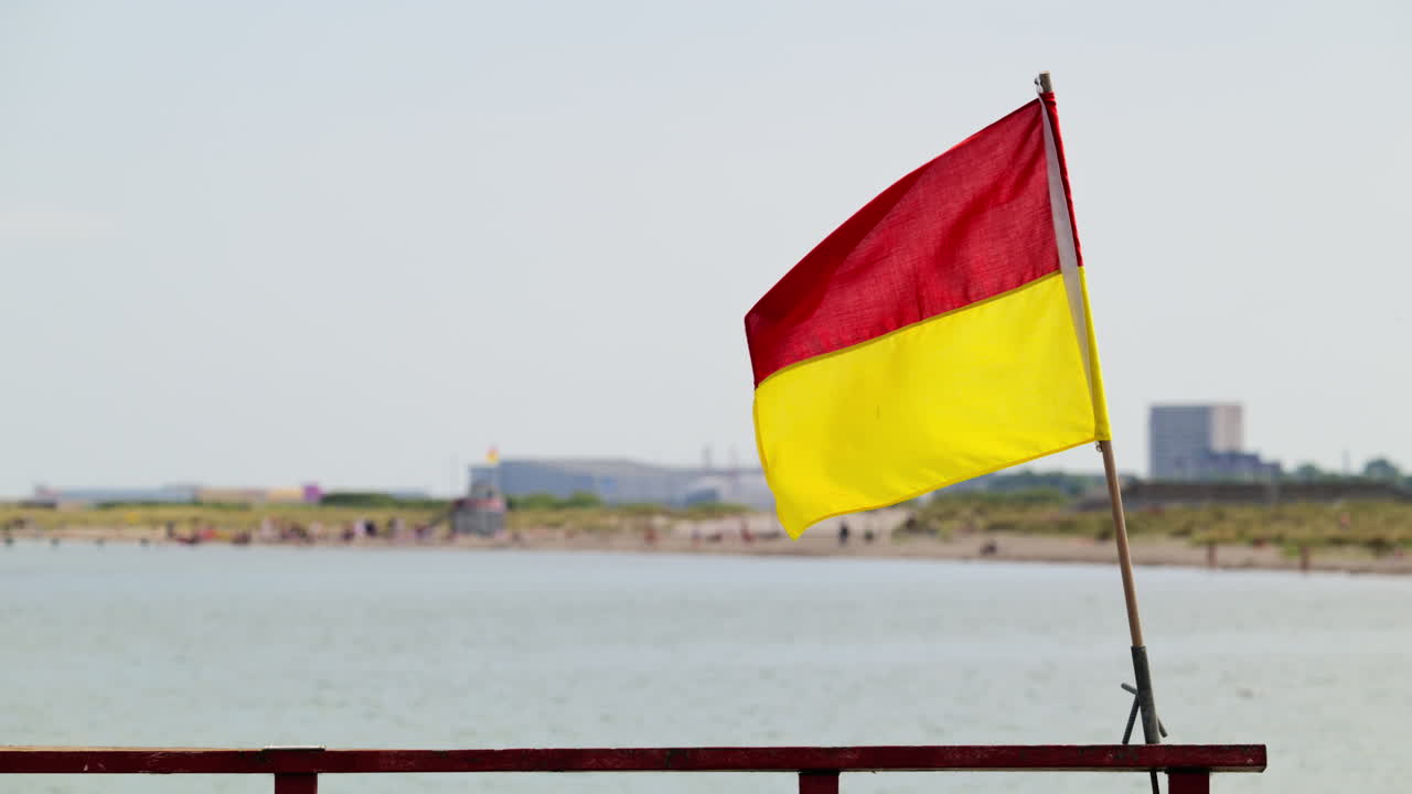Bandiera da bagnino che sventola su una spiaggia soleggiata, a indicare una zona balneabile sorvegliata. Copenaghen, Danimarca